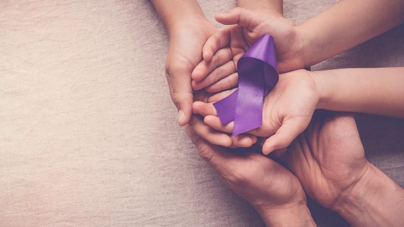 Adult and child hands holding purple ribbon, Alzheimer's disease, Pancreatic cancer, Epilepsy awareness, world cancer day