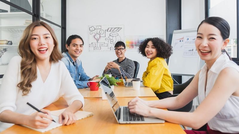 Group of smiling younger co-workers at a conference room table
