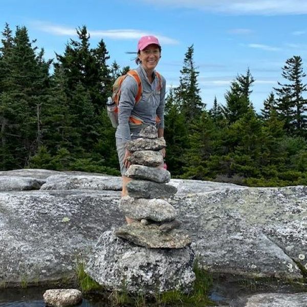 Jan McCaffery hiking behind a stack of stones in water